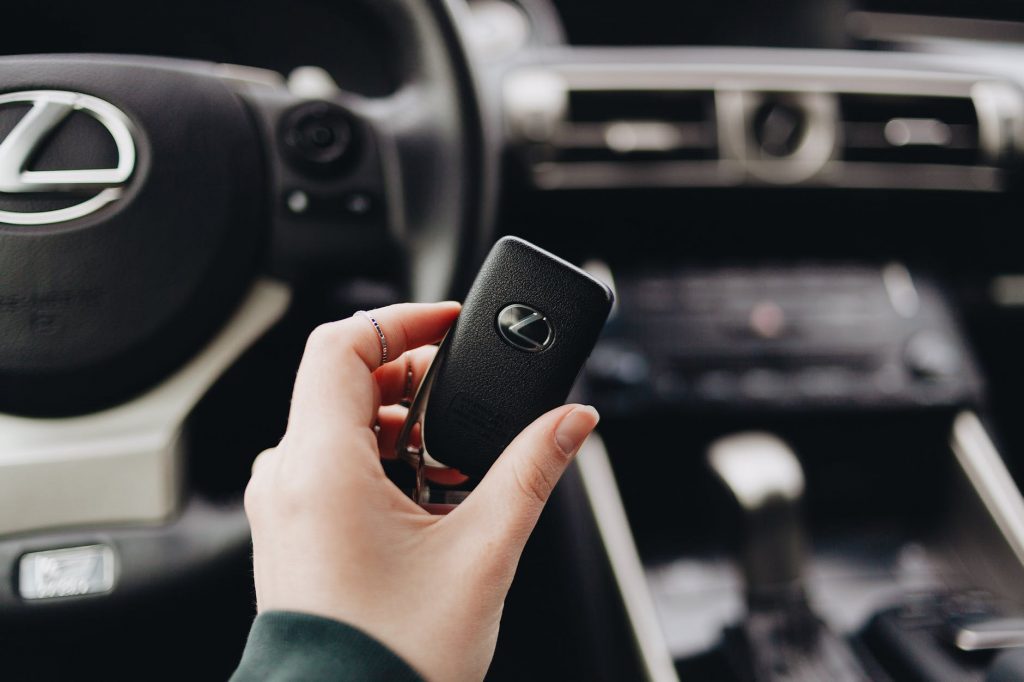 shallow focus photo of person holding a lexus car key