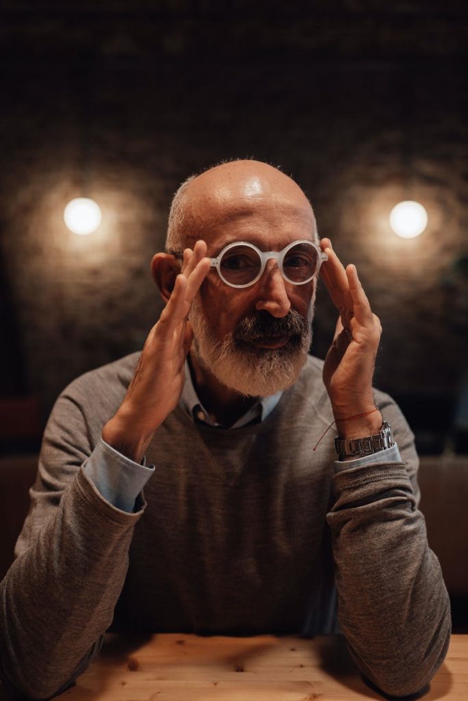 serious senior man adjusting eyeglasses